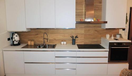 een keuken met witte kasten en een spoelbak bij Dimora Bohém in Cantù