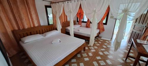 une chambre avec deux lits dans une pièce avec des rideaux dans l'établissement Chilly Beach Resort Palawan, à Aborlan