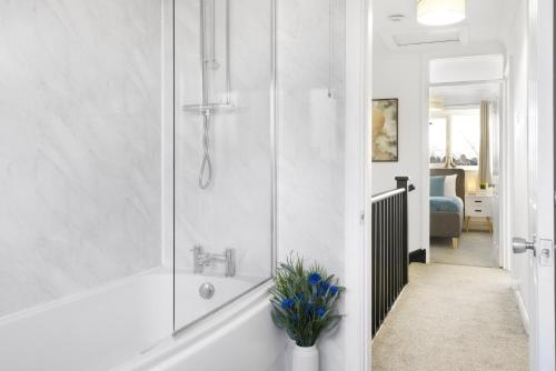ein weißes Badezimmer mit Dusche und Waschbecken in der Unterkunft 4 Bedroom Elegant House Near Peterborough City Center with Free Parking - Angus Suites by Contractor Lettings in Peterborough