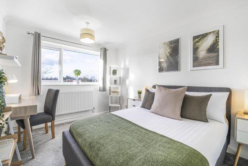 ein Schlafzimmer mit einem Bett und einem Schreibtisch und einem Schreibtisch in der Unterkunft 4 Bedroom Elegant House Near Peterborough City Center with Free Parking - Angus Suites by Contractor Lettings in Peterborough