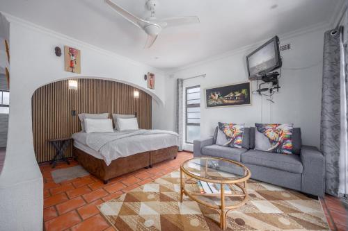 a bedroom with a bed and a couch and a tv at Beachcomber Bay Guest House In South Africa in Margate