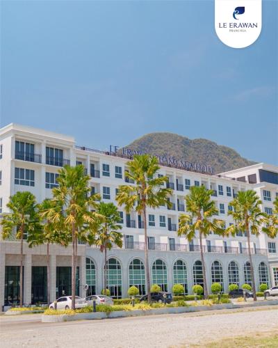 a large white building with palm trees in front of it at Le Erawan Phang Nga Hotel in Phangnga