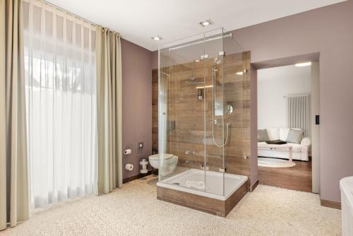 a bathroom with a shower with a toilet and a sink at Hotel Villa Lago in Bad Wiessee