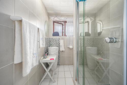 a bathroom with a shower and a toilet and a sink at Beachcomber Bay Guest House In South Africa in Margate