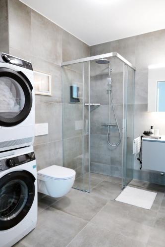 a bathroom with a washing machine and a toilet at Laya Living Lucerne - Kriens in Lucerne