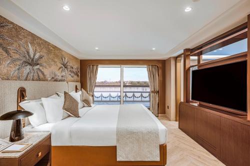 ein Schlafzimmer mit einem großen Bett und einem großen Fenster in der Unterkunft Sonesta St George Nile Cruise - Aswan to Luxor 3 Nights from Friday to Monday in Assuan