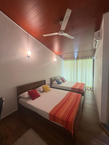 two beds in a room with a ceiling fan at Mount View Inn in Kandy