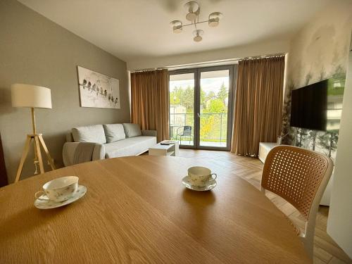 a living room with a table with two cups on it at Apartament Forest Elegance in Charzykowy