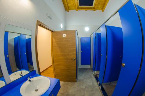 baño con compartimientos azules y lavamanos en Camping Playa de Ajo, en Ajo