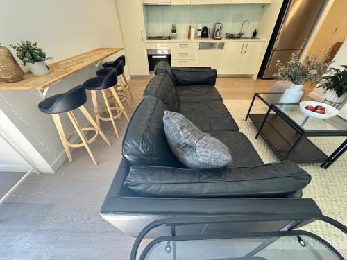 ein Wohnzimmer mit einem schwarzen Ledersofa und einer Küche in der Unterkunft Beautiful light filled modern apartment in Kew in Melbourne