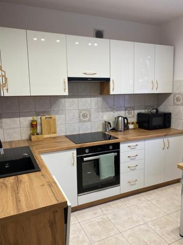 a kitchen with white cabinets and a stove top oven at Apartament Wysoka Brama in Lidzbark Warmiński