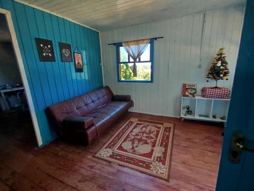 a living room with a leather couch and a window at Quarto N II Cama Individual e sofá cama solteiro in Gramado