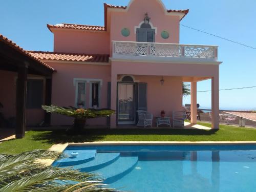 a villa with a swimming pool in front of a house at Casa do Poço Funchal in Funchal