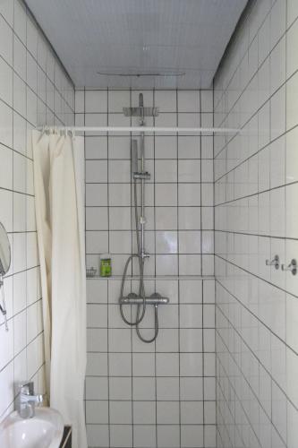 a shower in a white tiled bathroom with a sink at Grange habitée, nature & design in Manou