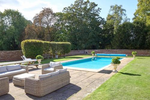 a swimming pool in a yard with couches at Abbey House by Group Retreats in Saffron Walden