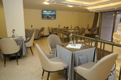 a dining room with tables and chairs and a television at Yofel Hotel Bole in Addis Ababa