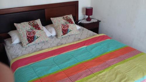 Una cama con una manta colorida y almohadas. en Cabañas Antomai, en Pichilemu