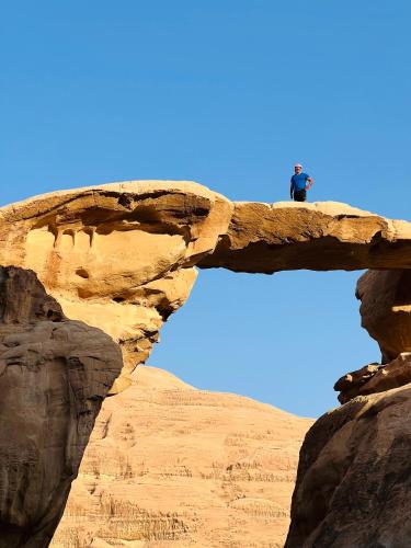 un homme debout au sommet d'un pont de pierre dans l'établissement Desert Key Camp, à Wadi Rum