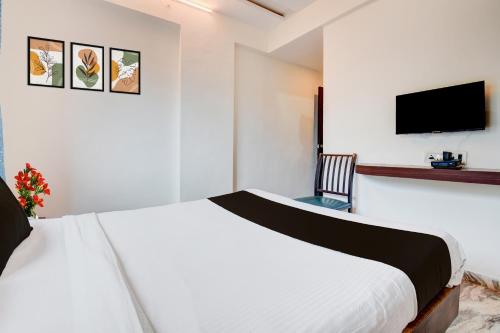 una camera da letto bianca con un letto e una TV a schermo piatto di Super Hotel O Khadakwasla Lakeview Formerly Gokul Lodge a Kharakvasla