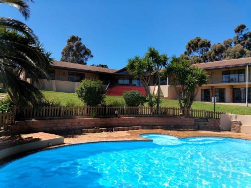 a swimming pool in front of a house at Into the Sunset Manor in Gordonʼs Bay