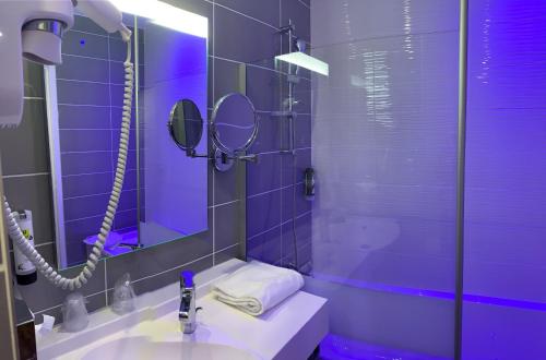 ein lila Badezimmer mit einem Waschbecken und einer Dusche in der Unterkunft Logis Hôtel-Restaurant LE FONTARABIE in Fontenay-le-Comte