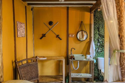 a room with a yellow wall with a sink and a mirror at Casa dos Hobbits: Lago, cascata, caiaque, piscina in Itatiba