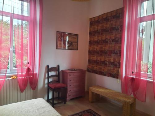 a bedroom with pink curtains and a chair and a dresser at Il Gelsomino "Meraviglioso appartamento in villa Liberty" in Gorizia