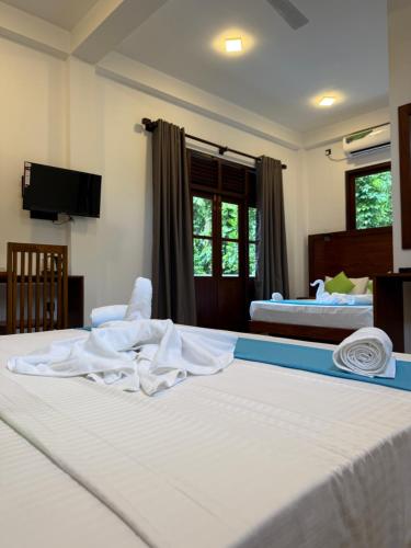 a hotel room with two beds with white sheets at Pearl Kingdom Hotel & Resort in Matara
