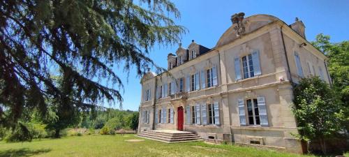 an old building with a red door in a field at Dordogne Chateau with Pool & Garden Sleeps 14 villa in Bourdeilles