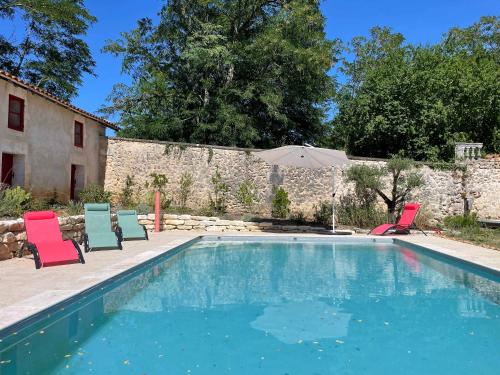 a swimming pool with two chairs and an umbrella at Dordogne Chateau with Pool & Garden Sleeps 14 villa in Bourdeilles