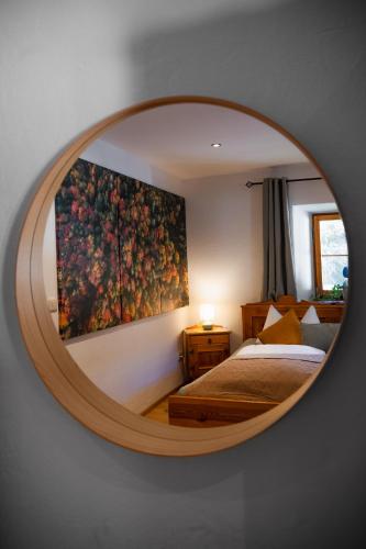 a mirror reflecting a bedroom with a painting on the wall at Natur Hof Schwarnlehen in Berchtesgaden