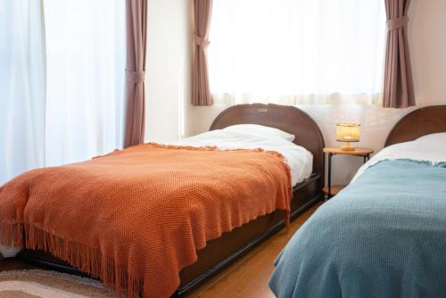 a bedroom with two beds and a window at 湯治宿かふね in Yugawara