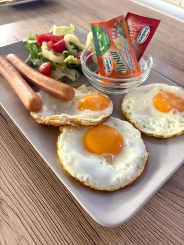Un plato con tres huevos fritos y una ensalada. en Budapest Airport Almáskert Panzió, en Vecsés