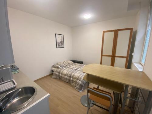 une chambre avec un lit, une table et un lavabo dans l'établissement Le pied du Beffroi d'Arras, à Arras