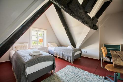 a attic bedroom with two beds and a window at Altes Fährhaus - Ferienwohnung Boven, 220 qm in Wewelsfleth