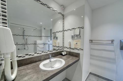 ein weißes Badezimmer mit Waschbecken und Spiegel in der Unterkunft Hotel Restaurant Le Gardon - Pont du Gard in Collias