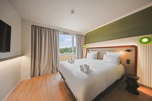 une chambre avec un grand lit et une grande fenêtre dans l'établissement Campanile PRIME - Smart Lyon Chaponost, à Chaponost