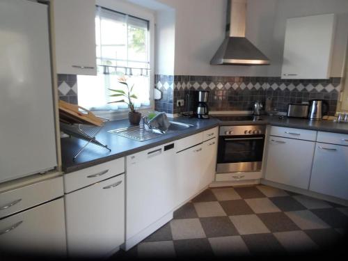 une cuisine avec des armoires blanches et un évier dans l'établissement Ferienhaus Mit Garten Und Stellplatz, à Großenaspe