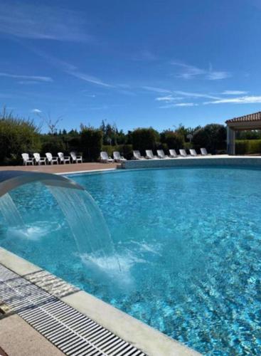 a large blue swimming pool with chairs in the background at Maison Les Demeures du Ventoux in Aubignan