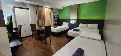 马尼拉Lorenzzo Suites Hotel Makati的一间设有两张床和绿色墙壁的客房