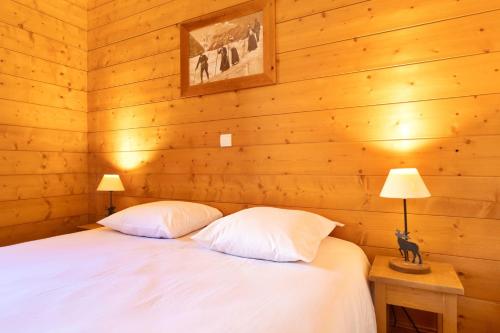 尚帕尼恩瓦努瓦茲Pralioud – Confort moderne, spa & piscine的一间卧室配有一张带两个枕头和两个灯的床。