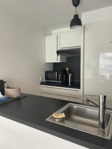 a kitchen with a sink and a microwave at Parenthèse d'Opale Hardelot in Neufchâtel-Hardelot
