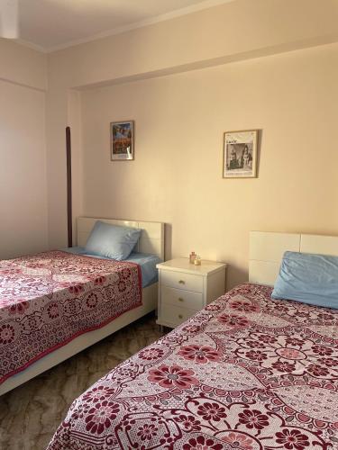 a bedroom with two beds and a night stand at Gîte Hôtel Ramla Louxor 2 in Luxor