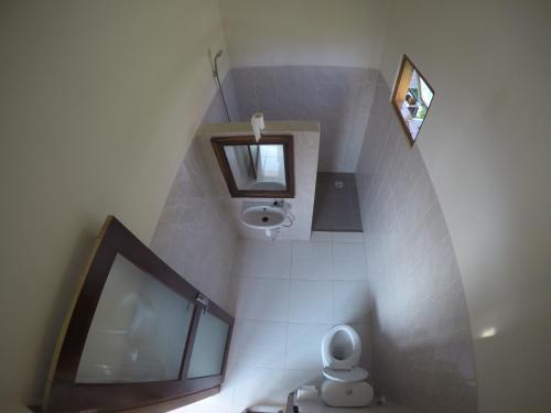 a small bathroom with a toilet and a mirror at Homestay & Restaurant Segara Amed in Amed