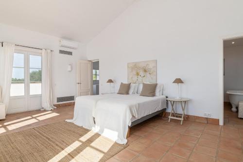 ein weißes Schlafzimmer mit einem großen Bett und einer Badewanne in der Unterkunft Villa Albatros in Benalup Casas Viejas