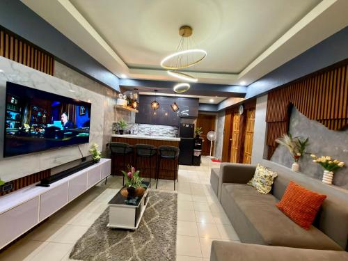 Una sala de estar con un televisor grande y un sofá. en Baguio Transient Across Burnham Park 2 - 2BR Condo, en Baguio
