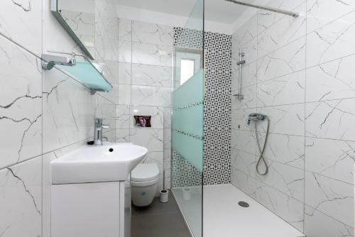 une salle de bain blanche avec lavabo et douche dans l'établissement Apartments Antonio, à Duće