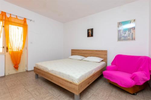 une chambre avec un lit et une chaise rose dans l'établissement Apartments Antonio, à Duće