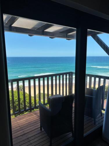 a room with a view of the ocean from a balcony at Dolphin Dunes Guesthouse in Wilderness