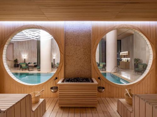 a wellness room with a pool and a circular mirror at Swissôtel Tbilisi in Tbilisi City